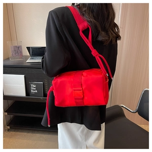 Macro shot of red nylon crossbody bag with buckle detail and knotted shoulder strap