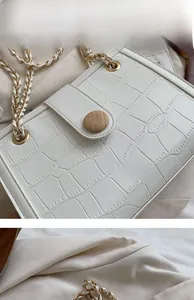 Close-up of white crocodile embossed leather bag featuring vintage gold chain strap