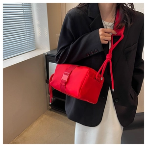 Detail of red nylon crossbody bag featuring stylish plastic buckle and knotted rope strap