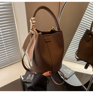 Close-up of deep brown lychee grain leather bucket bag with decorative printed silk scarf handle