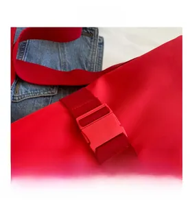 Detailed close-up of the red nylon bag's durable plastic buckle and reinforced strap