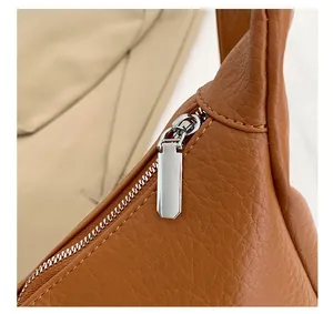 Close-up of a silver rectangular zipper on a brown textured leather tote bag
