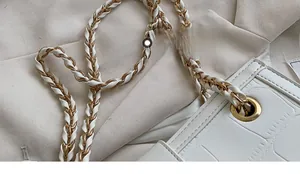 Detailed macro view of stylish golden chain strap on a white crocodile embossed handbag