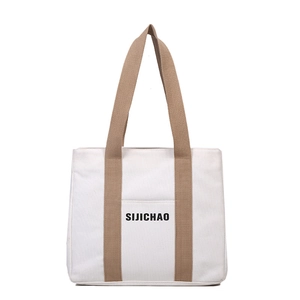 Minimalist cream canvas tote bag with brown straps and front pocket for daily commute