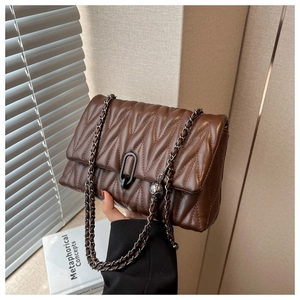 Detailed macro of dark brown quilted leather bag with silver chain and metal clasp