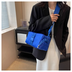 Macro shot of vibrant blue nylon crossbody bag with woven rope strap and plastic buckle detail