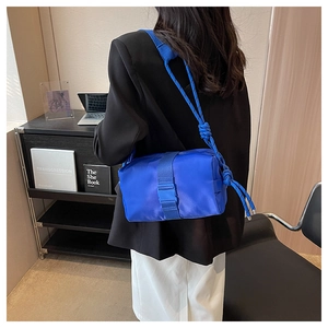 Detail of bright blue nylon crossbody bag featuring chunky knotted rope shoulder straps