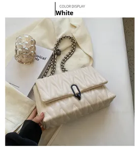 Detail of cream quilted crossbody bag with V-stitch pattern and black metallic clasp