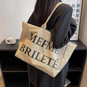 Grand sac cabas en toile beige avec lettrage noir porté à l'épaule pour le quotidien