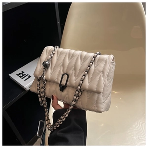 Close-up of cream quilted crossbody bag featuring V-shaped texture and black chain strap