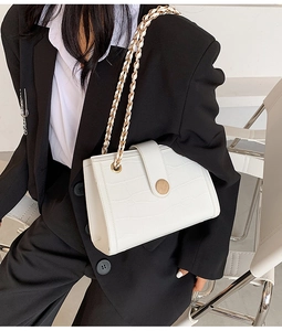 Detail of white crocodile pattern shoulder bag with a round wood-grain button and chain strap