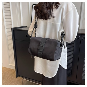 Detail of black nylon crossbody bag featuring large plastic buckle and knotted rope strap