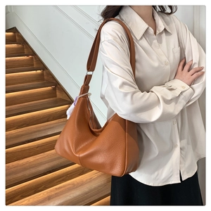 Close-up of brown lychee leather Hobo bag worn over shoulder with sleek metal zipper