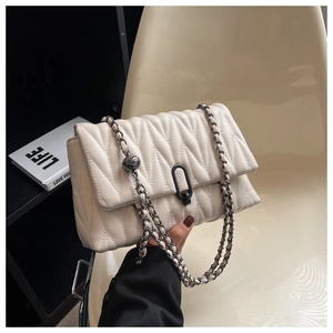 Close-up of beige quilted crossbody bag with V-pattern and black U-shaped lock