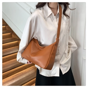 Close-up of brown lychee texture leather tote bag worn by model on shoulder