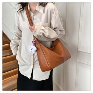Brown pebble leather tote bag with white star plush charm shown on model in interior
