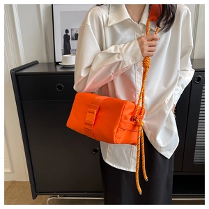 Detail of bright orange nylon crossbody bag with thick climbing rope strap on model