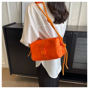 Detail of bright orange nylon crossbody bag with three-color woven rope strap and buckle
