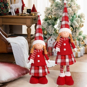 Detailed view of two Christmas girl dolls in festive red outfits by a holiday tree