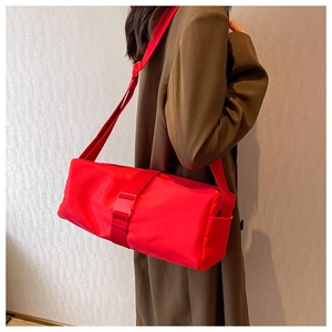 Side view of a bright red nylon crossbody bag with large plastic buckle on model