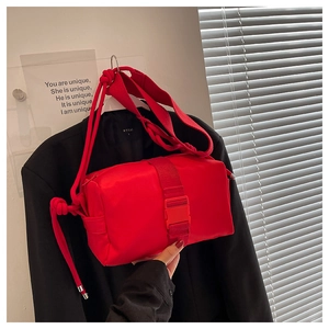 Detail of vibrant red nylon crossbody bag with wide knotted strap and buckle closure