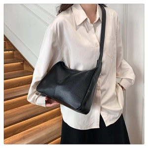 Detail of black pebbled leather tote bag with vertical stitching on vintage shoulder bag