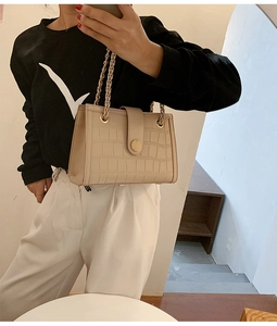 Close-up of cream crocodile pattern bag with metal chain strap and round buckle