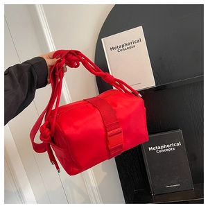 Detail of red nylon crossbody bag with woven rope strap and buckle closure