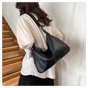 Detail of black lychee grain tote bag with silver hardware and plush white charm decoration