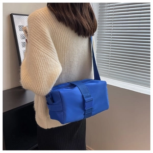 Model view of a bright blue nylon crossbody bag with adjustable buckle strap and casual fit
