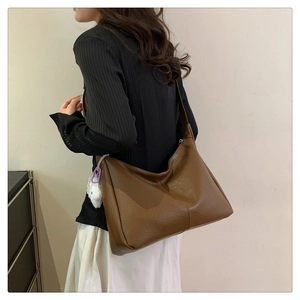 Brown leather tote bag with lychee texture and white fur ball pendant on model