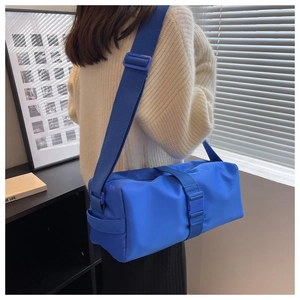 Detail of Klein blue cylindrical nylon crossbody bag showing wide strap and buckle detail