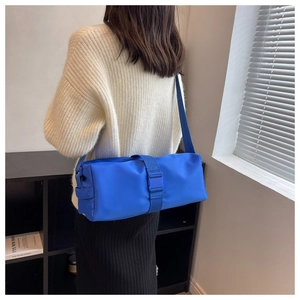 Blue nylon cylinder crossbody bag shown on a model highlighting its large capacity design