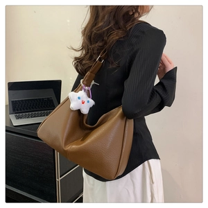 Brown leather hobo tote bag with plush star charm shown in an office setting