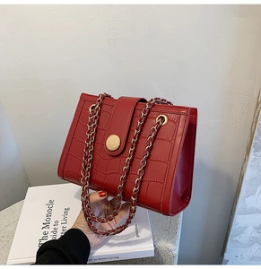 Detail of red crocodile texture wedding bag with wooden buckle and golden chain strap
