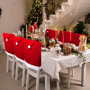 Detail of red velvet Santa hat chair covers in a cozy Christmas dining room setting