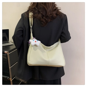Detail of beige leather hobo bag with star plush charm on a model in a black blazer