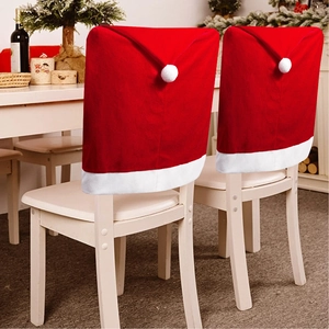 Detail of red velvet Santa hat chair covers with white pompoms on wooden dining chairs