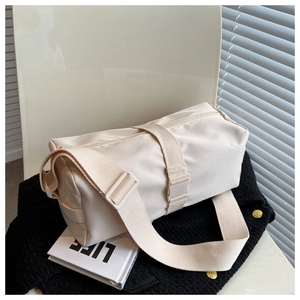 Detail view of beige nylon cylinder bag with adjustable wide shoulder strap and matte finish