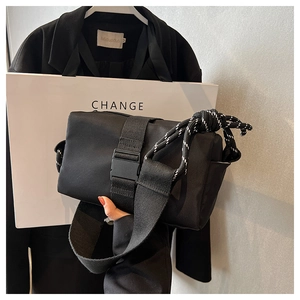 Detail of black nylon crossbody bag with buckle closure and climbing rope handle