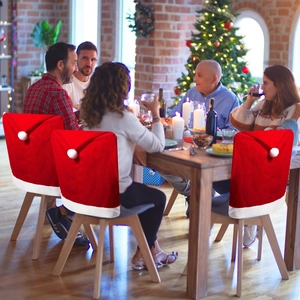 Close-up of red velvet Santa hat chair covers with white plush trim for Christmas dining