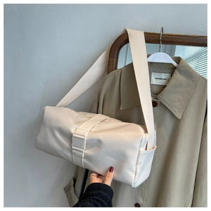 Detail of a cream nylon crossbody bag with buckle closure in a lifestyle setting