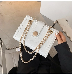 Macro shot of white crocodile texture purse with wooden buckle and golden chain strap