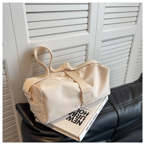 Chic cream nylon cylinder bag displayed on a black leather sofa with urban styling