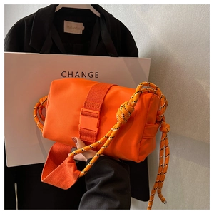 Detailed shot of an orange nylon crossbody bag with woven rope and plastic buckle closure