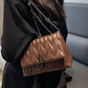 Brown quilted chain bag for women with V-shaped stitching shown on a shoulder