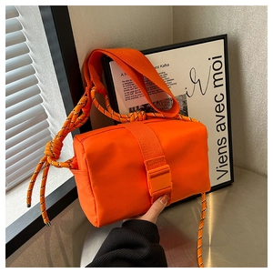 Detail of bright orange nylon crossbody bag with tactical buckle and woven strap