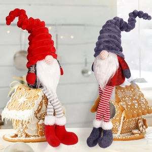 Close-up of plush Christmas gnomes sitting on gingerbread houses in warm home decor