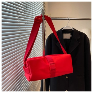 Detailed view of red nylon crossbody bag with wide shoulder strap and plastic buckle closure