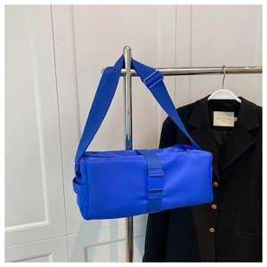 Detail of blue nylon crossbody bag with adjustable buckle strap on display rack